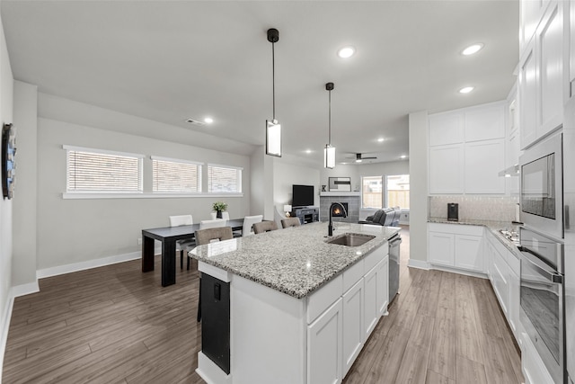 kitchen with appliances with stainless steel finishes, sink, tasteful backsplash, white cabinetry, and a kitchen island with sink