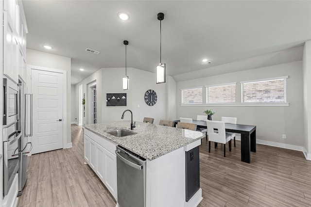 kitchen featuring a kitchen island with sink, light stone countertops, sink, appliances with stainless steel finishes, and white cabinets