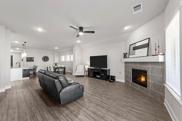 living room featuring a fireplace, ceiling fan, sink, and wood-type flooring