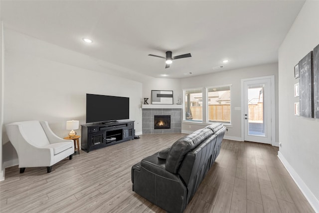 living room with a fireplace, ceiling fan, and light hardwood / wood-style floors