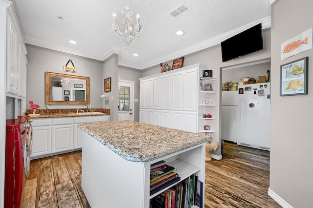 kitchen featuring white cabinets, a kitchen island, white fridge, and wood-type flooring