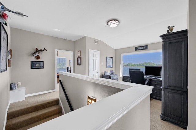 hallway featuring light colored carpet and vaulted ceiling