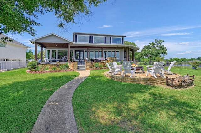 rear view of house with a yard, a fire pit, and a patio