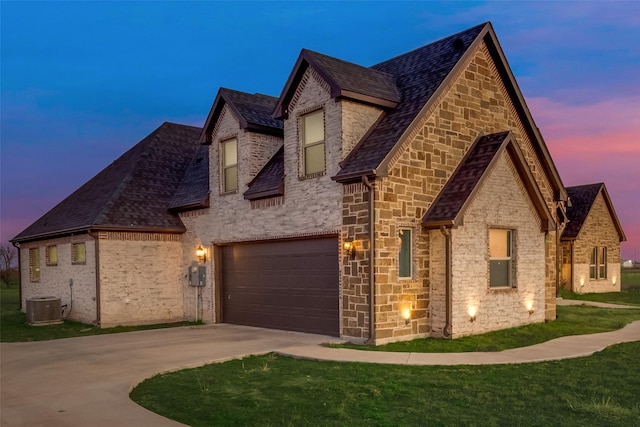 french country style house with a garage, a yard, and central AC