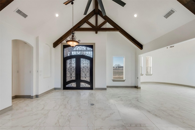 unfurnished living room featuring a stone fireplace, high vaulted ceiling, beamed ceiling, ceiling fan, and french doors