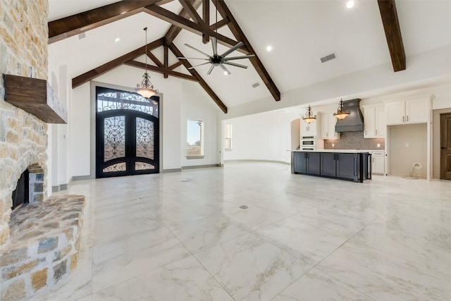 living room featuring a fireplace, high vaulted ceiling, beamed ceiling, ceiling fan, and french doors