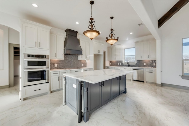 kitchen featuring pendant lighting, appliances with stainless steel finishes, white cabinets, and premium range hood