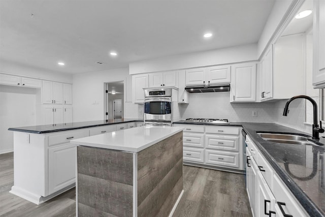 kitchen featuring decorative backsplash, sink, a kitchen island, white cabinets, and dark hardwood / wood-style flooring