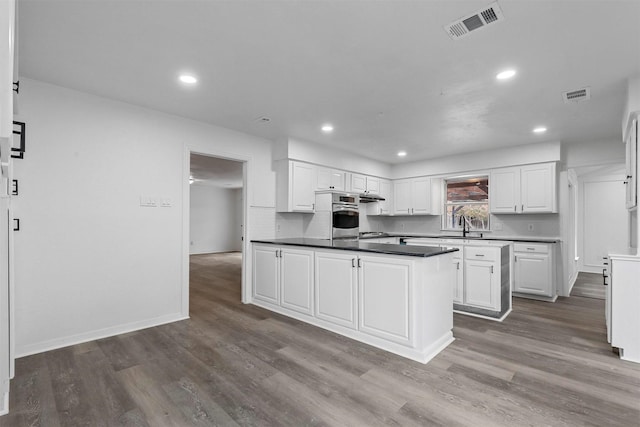 kitchen with white cabinets, tasteful backsplash, dark hardwood / wood-style floors, and oven