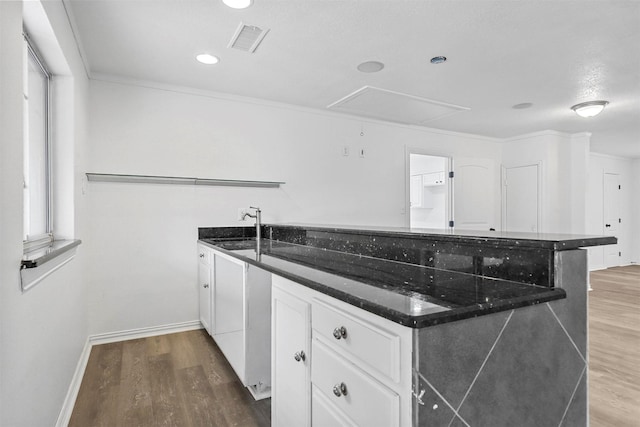 kitchen with sink, hardwood / wood-style flooring, white cabinetry, and crown molding