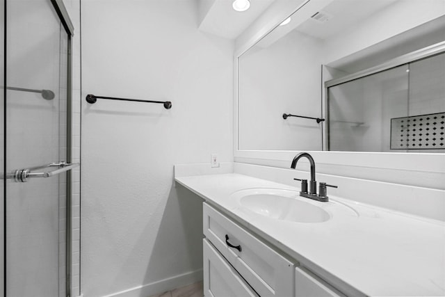 bathroom featuring a shower with shower door and vanity