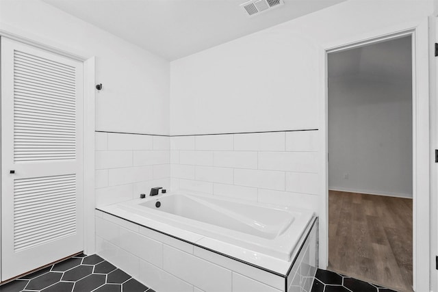 bathroom with a relaxing tiled tub and tile patterned flooring