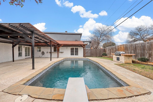 view of swimming pool featuring a patio, an outdoor kitchen, a pergola, and a diving board