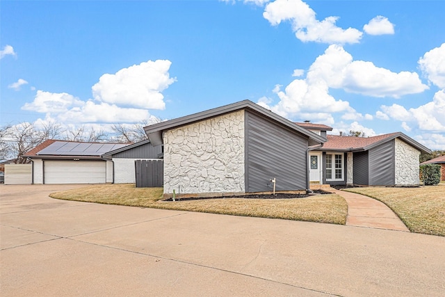 view of property exterior featuring a garage, a lawn, and solar panels