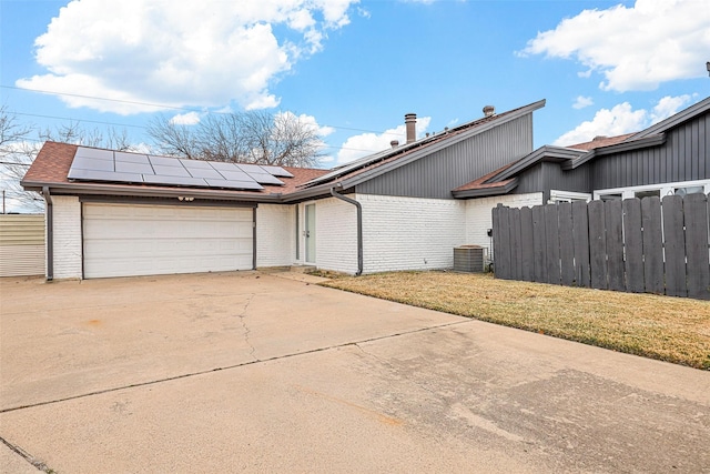 exterior space with a garage, a front yard, solar panels, and central air condition unit