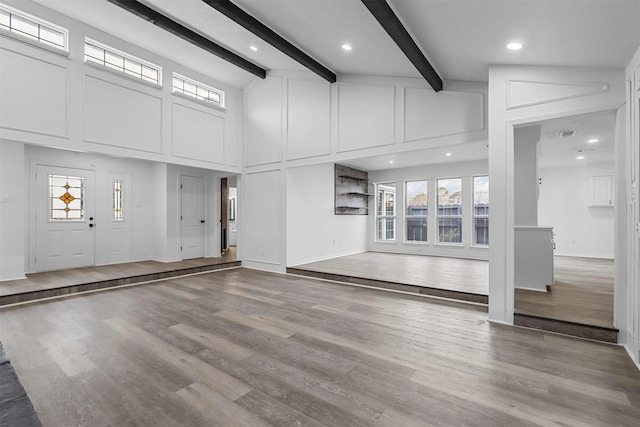 unfurnished living room featuring hardwood / wood-style flooring, a towering ceiling, and beamed ceiling