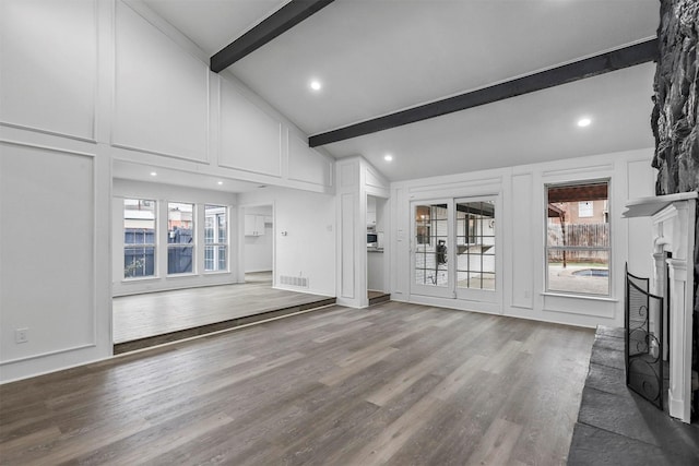 unfurnished living room with hardwood / wood-style flooring and vaulted ceiling with beams