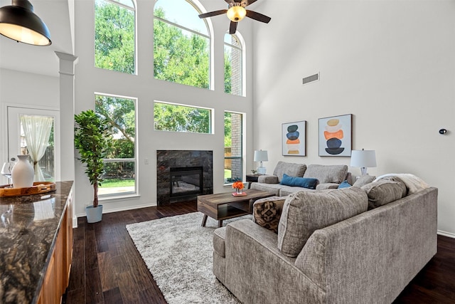 living room with dark wood-type flooring, a high ceiling, ceiling fan, and a premium fireplace