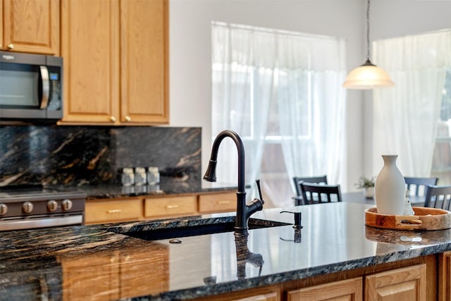 kitchen with pendant lighting, stainless steel range oven, dark stone countertops, decorative backsplash, and sink