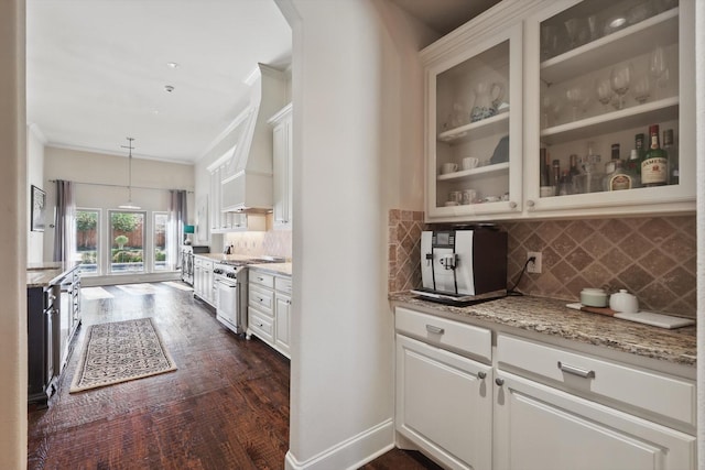 kitchen with high end range, white cabinetry, light stone countertops, ornamental molding, and decorative light fixtures