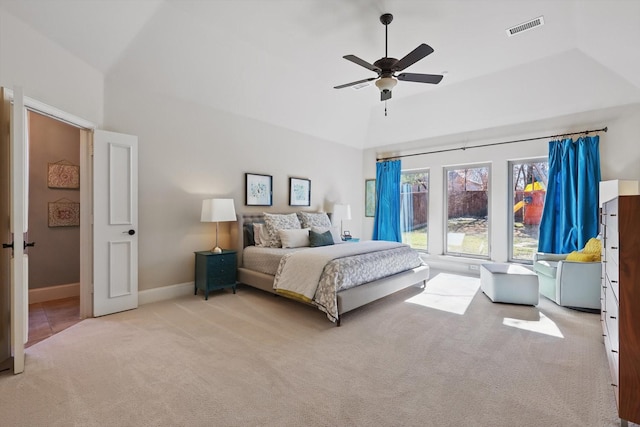 carpeted bedroom with a tray ceiling, vaulted ceiling, and ceiling fan