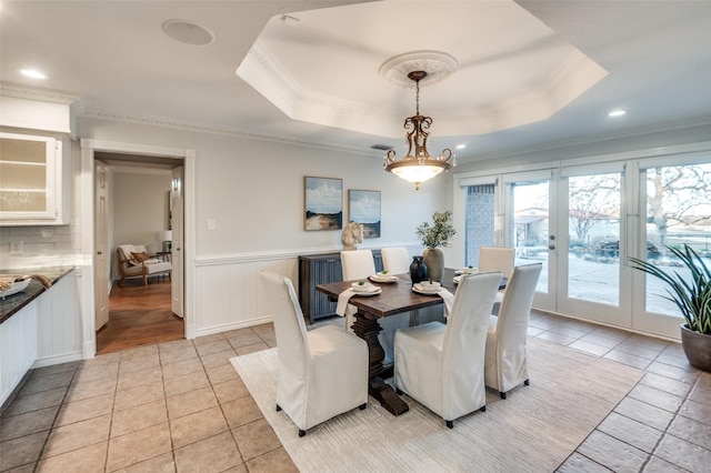 tiled dining room with a tray ceiling and ornamental molding