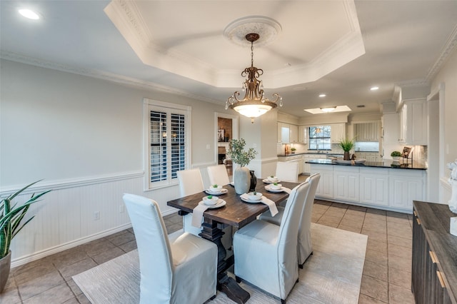 tiled dining area with a raised ceiling and crown molding