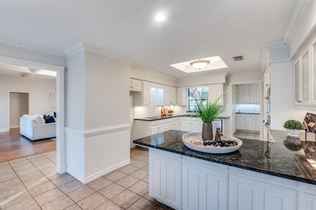 kitchen featuring dark stone countertops, white cabinetry, kitchen peninsula, and light tile patterned floors