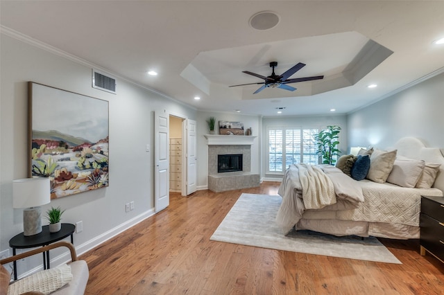 bedroom with ceiling fan, a tray ceiling, light hardwood / wood-style flooring, and crown molding