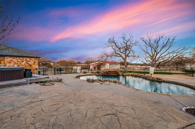 pool at dusk featuring a patio and a hot tub