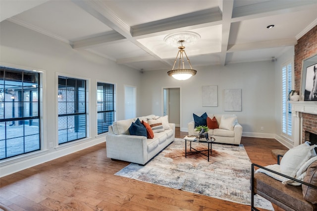 living room featuring beamed ceiling, hardwood / wood-style floors, coffered ceiling, a brick fireplace, and ornamental molding