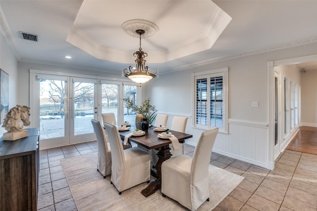 dining space featuring crown molding, light tile patterned floors, and a tray ceiling