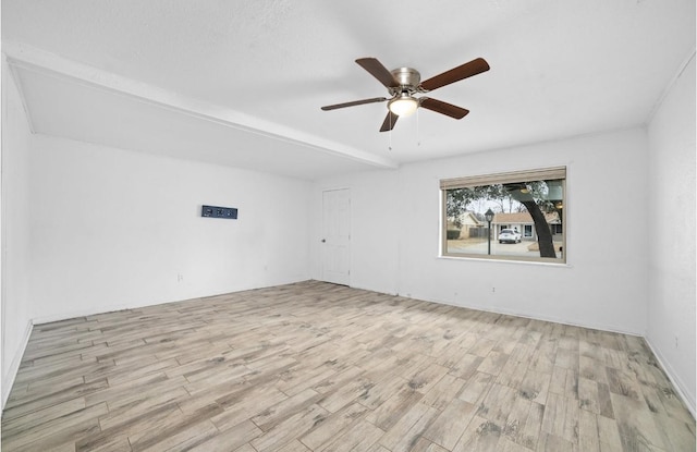 spare room featuring light wood-type flooring, beamed ceiling, and ceiling fan