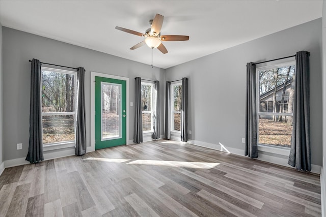 unfurnished room featuring light wood-type flooring, ceiling fan, and a wealth of natural light