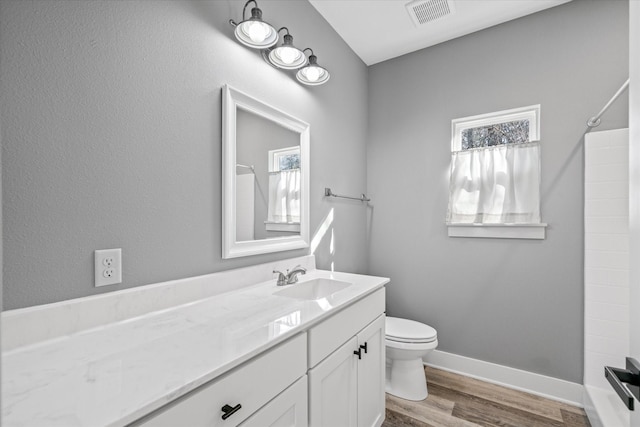 bathroom with a shower, hardwood / wood-style floors, toilet, and vanity