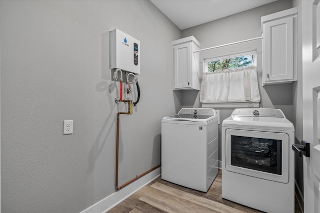 washroom with washing machine and dryer, light hardwood / wood-style flooring, and cabinets