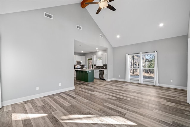 unfurnished living room with beam ceiling, ceiling fan, high vaulted ceiling, and light hardwood / wood-style flooring