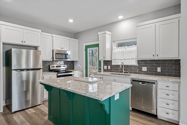 kitchen featuring sink, white cabinets, light stone counters, a center island, and stainless steel appliances