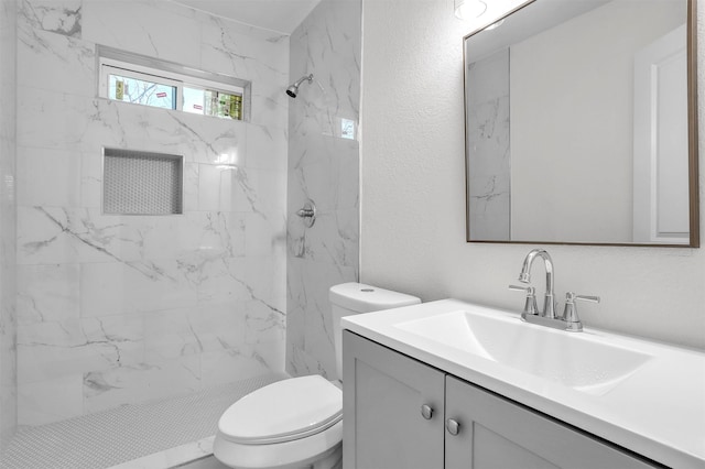 bathroom with tiled shower, vanity, and toilet