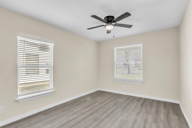 spare room with ceiling fan, light wood-type flooring, and a wealth of natural light