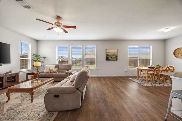 living room with dark wood-type flooring, plenty of natural light, and ceiling fan