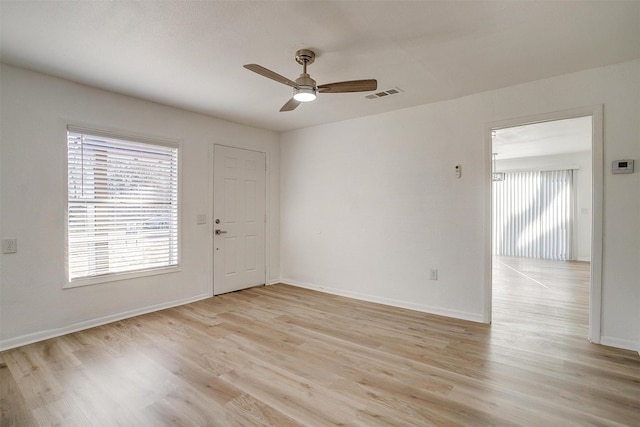 empty room with plenty of natural light, light hardwood / wood-style flooring, and ceiling fan