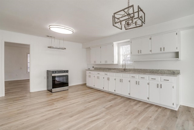 kitchen with hanging light fixtures, stainless steel electric range, sink, and white cabinets