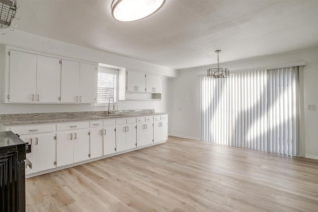 kitchen with sink, white cabinetry, light hardwood / wood-style flooring, and hanging light fixtures