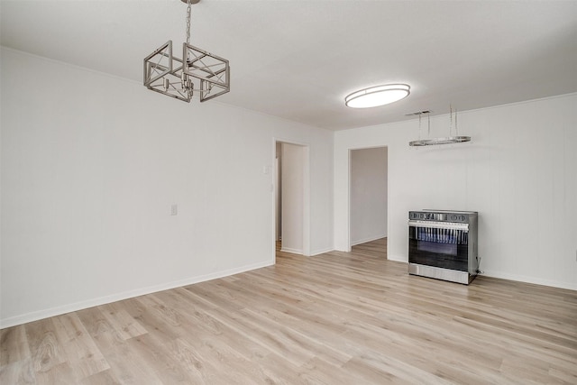 unfurnished living room featuring an inviting chandelier, heating unit, and light hardwood / wood-style floors