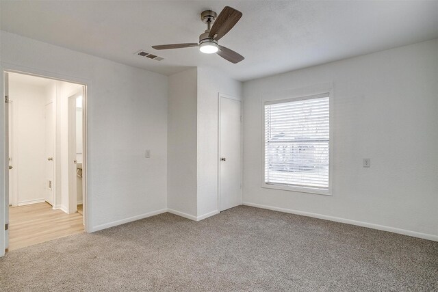 unfurnished bedroom with ensuite bath, light colored carpet, and ceiling fan