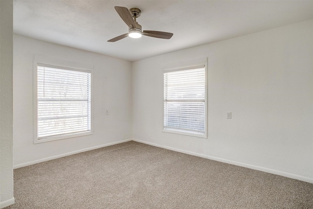 carpeted empty room featuring ceiling fan and a wealth of natural light