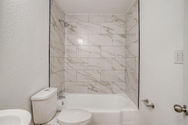 bathroom with tiled shower / bath combo and toilet