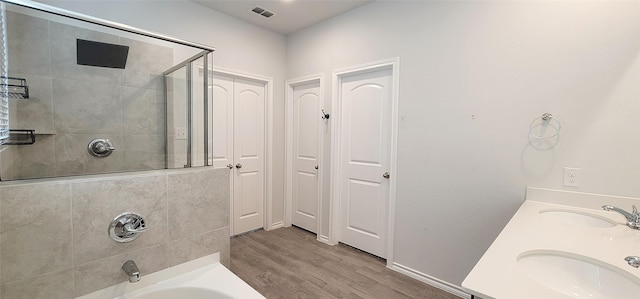 bathroom with tiled shower / bath combo, hardwood / wood-style flooring, and vanity