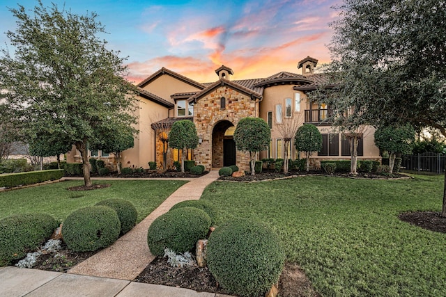 mediterranean / spanish house with a balcony and a lawn